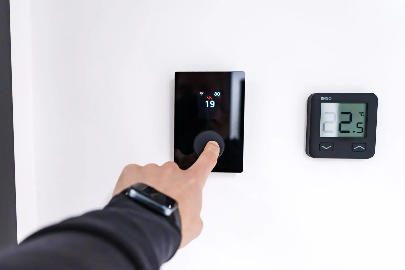 Hand adjusting a modern wall thermostat